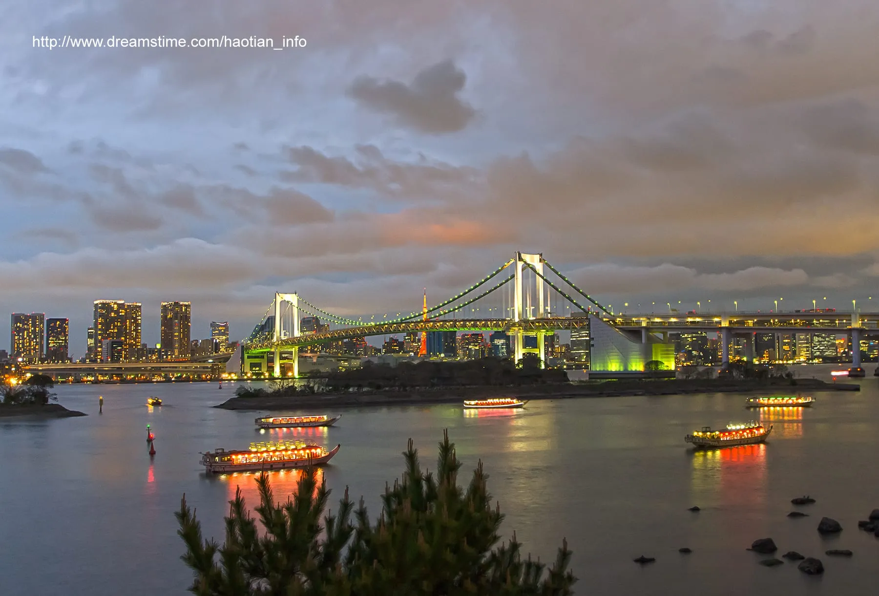 Yakatabune boats moored on Tokyo Bay at dusk with Rainbow Bridge behind